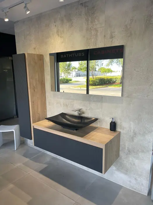Modern bathroom vanity showroom display featuring a black vessel sink on natural wood countertop with integrated storage base and framed mirrors
