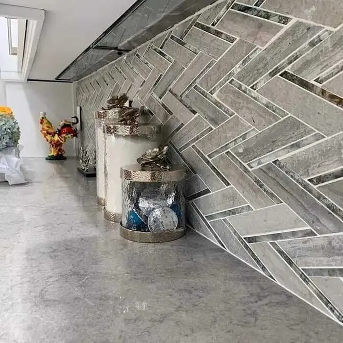Close-up detail of herringbone pattern tile flooring with gray and white tones, sample display bucket in foreground against finished floor installation