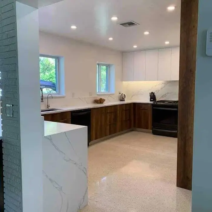 Modern kitchen with white upper cabinetry, dark wood lower cabinetry, marble-effect countertops, and recessed lighting