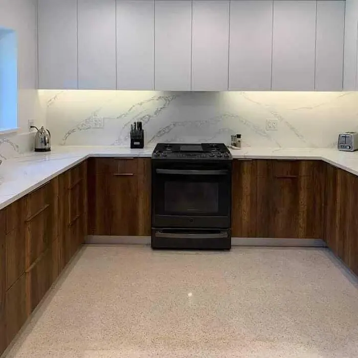 Cocina moderna completada con gabinetes de madera cálida, backsplash de mármol blanco con iluminación bajo los gabinetes, encimeras de cuarzo blanco y estufa de gas negra.